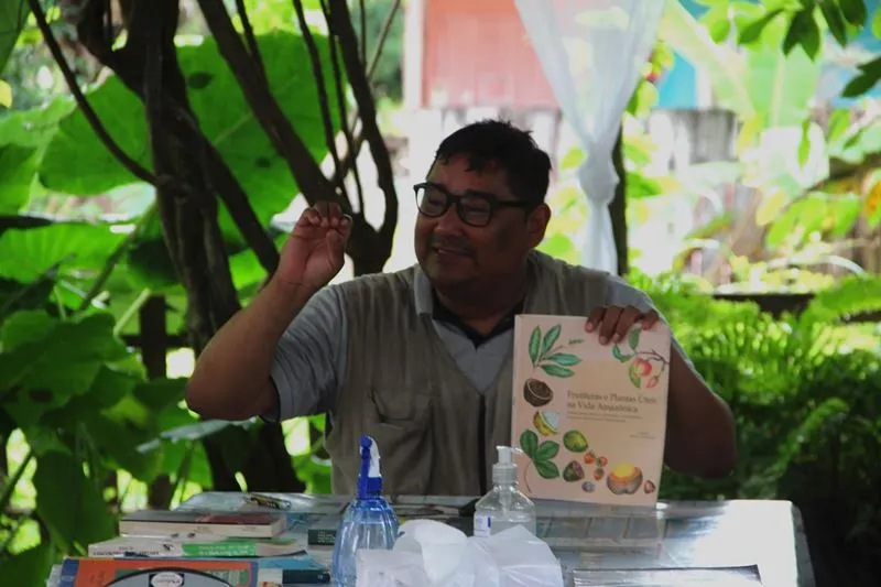 Richardson Frazão com um livro e explicando em uma mesa
